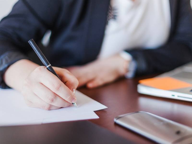 man writting in a document sitting at a table