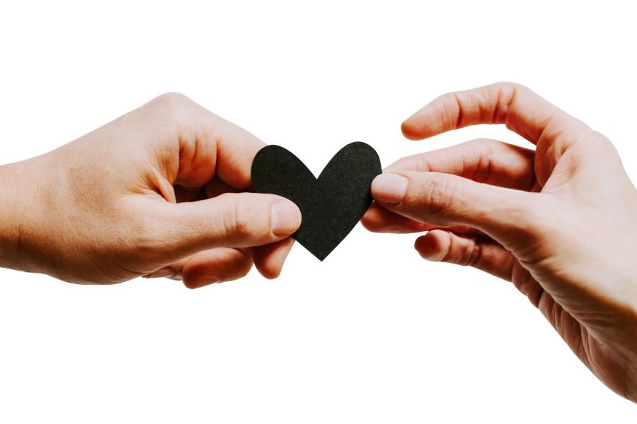 Two hands hold a black heart with the word love on it